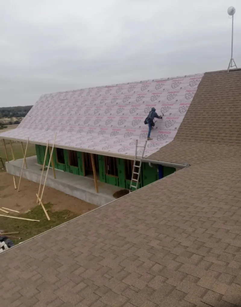 Worker preparing underlayment for a metal roof installation in Lower Windsor